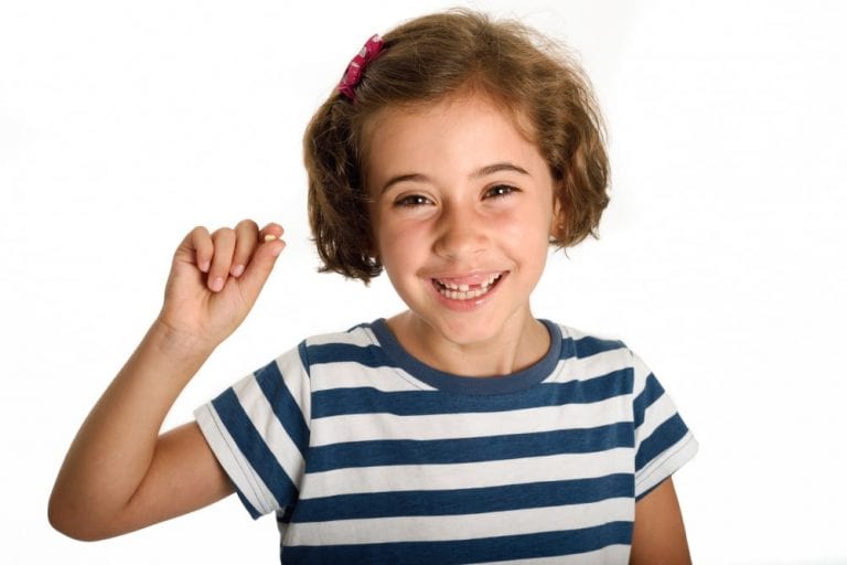 criança feliz mostrando seu dente de leite que caiu