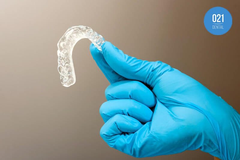 Dentista segurando placa de bruxismo entre seus dedos